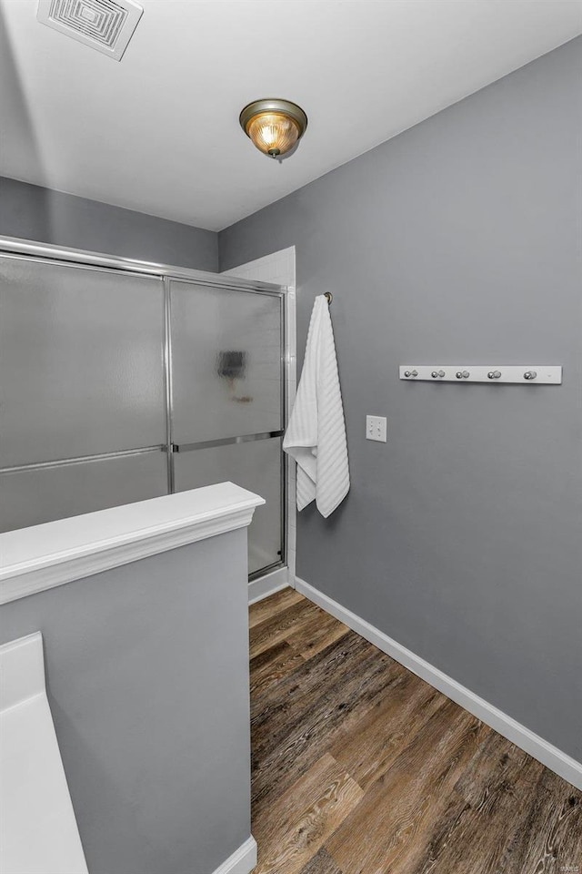 bathroom featuring baseboards, wood finished floors, visible vents, and a shower stall