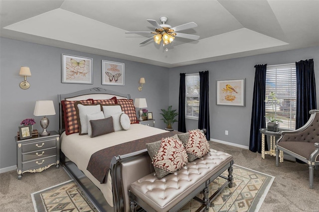 bedroom featuring a tray ceiling, carpet flooring, ceiling fan, and baseboards