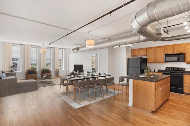 kitchen featuring open floor plan, black appliances, light wood-type flooring, and dark countertops