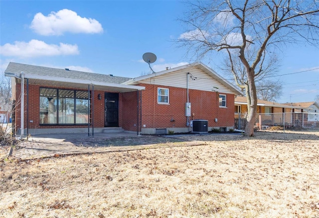 back of property with brick siding, central AC unit, and fence