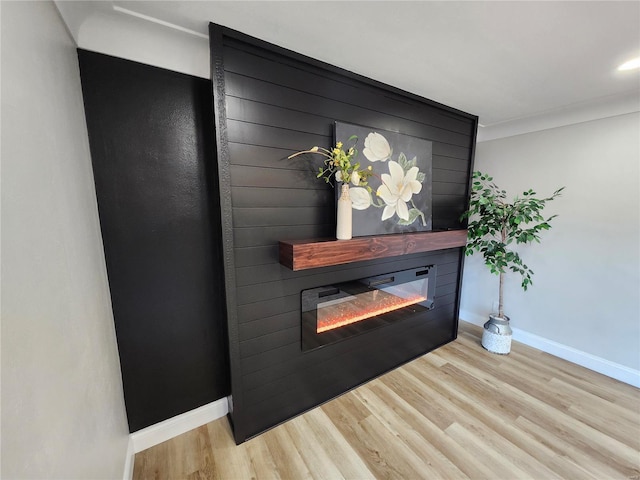 details with a large fireplace, baseboards, and wood finished floors