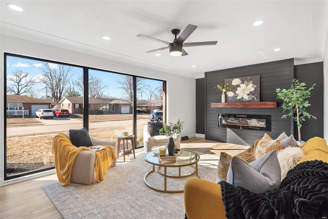 living room featuring recessed lighting, wood finished floors, a ceiling fan, baseboards, and a glass covered fireplace