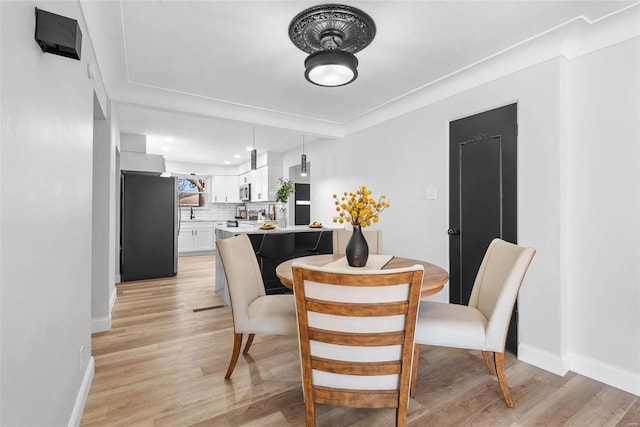 dining room with light wood-type flooring, visible vents, and baseboards