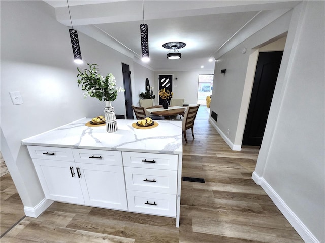 kitchen with baseboards, light wood finished floors, white cabinetry, and light stone countertops