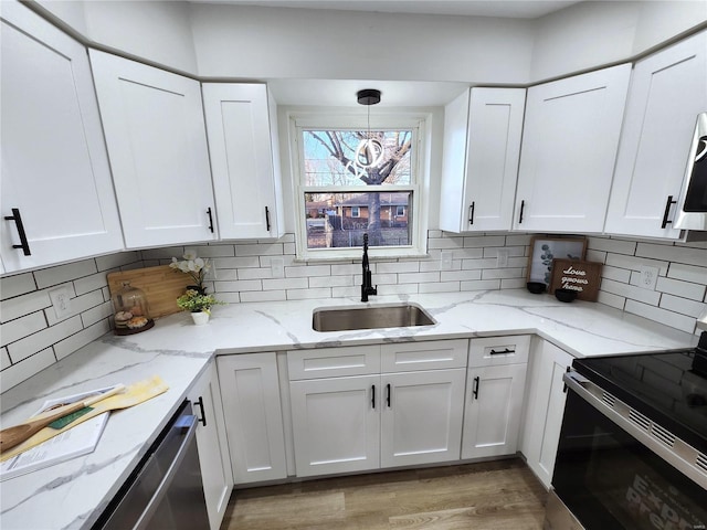 kitchen featuring backsplash, appliances with stainless steel finishes, white cabinets, and a sink