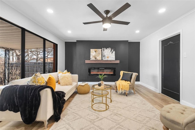 living area featuring ornamental molding, a glass covered fireplace, recessed lighting, and wood finished floors