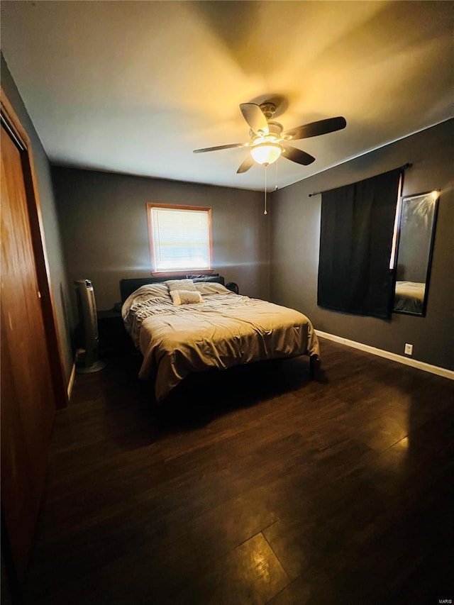 bedroom featuring a closet, wood finished floors, a ceiling fan, and baseboards