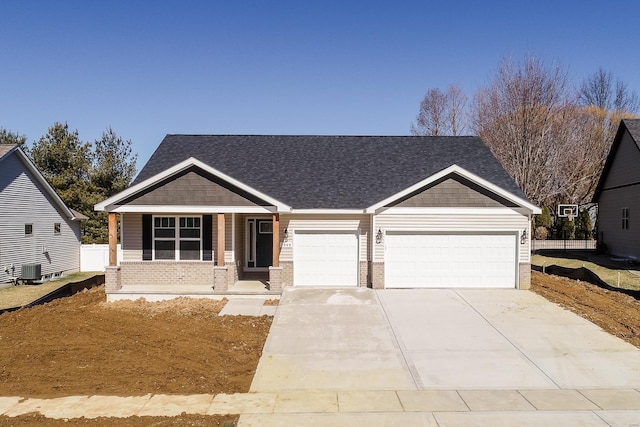 craftsman inspired home featuring a garage, concrete driveway, brick siding, and central AC unit