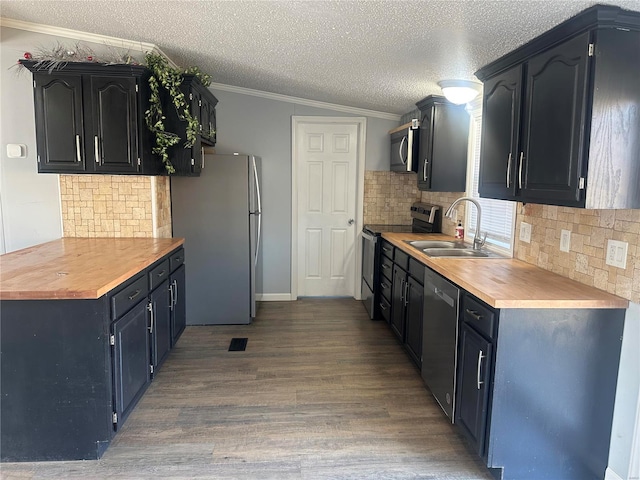 kitchen featuring light wood finished floors, appliances with stainless steel finishes, ornamental molding, a sink, and a textured ceiling