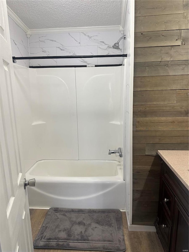 bathroom with a textured ceiling, wood walls, shower / bath combination, wood finished floors, and vanity