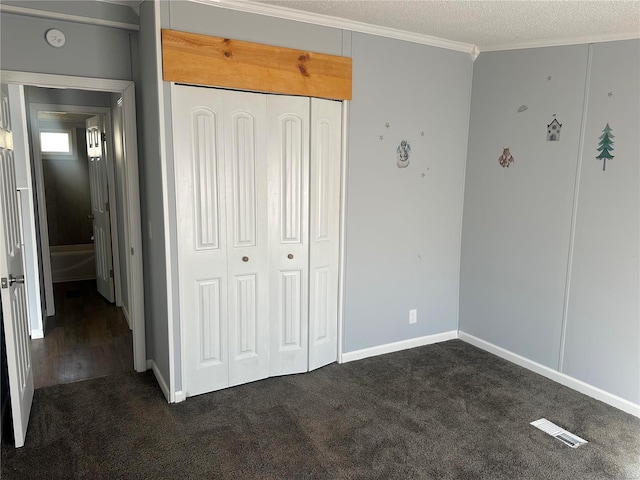 unfurnished bedroom with crown molding, dark colored carpet, a closet, visible vents, and a textured ceiling