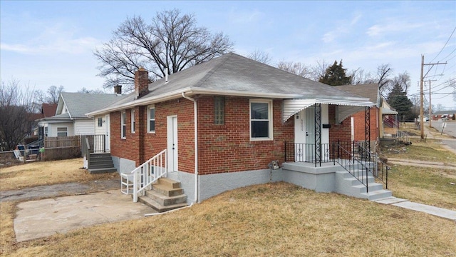 bungalow-style house featuring entry steps, brick siding, a chimney, fence, and a front yard