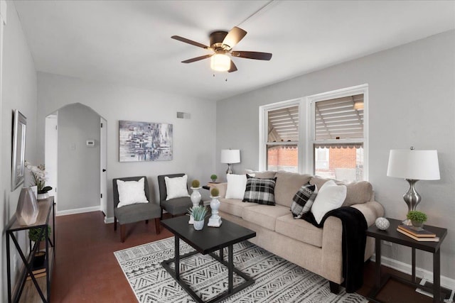 living room with arched walkways, visible vents, a ceiling fan, wood finished floors, and baseboards