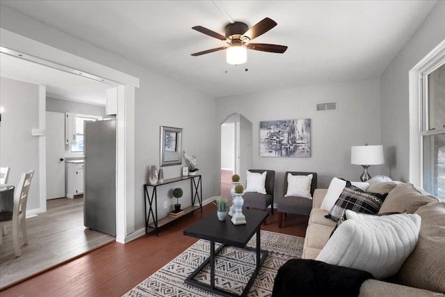 living area featuring baseboards, visible vents, arched walkways, ceiling fan, and wood finished floors