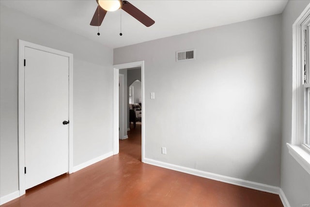 unfurnished bedroom featuring baseboards, visible vents, arched walkways, and a ceiling fan