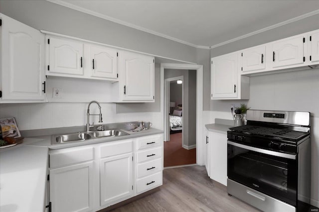 kitchen with light countertops, gas stove, a sink, and white cabinets