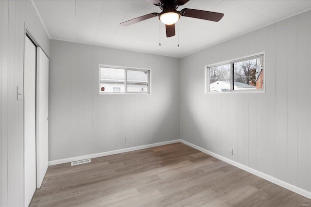 unfurnished bedroom featuring multiple windows, wood finished floors, and visible vents