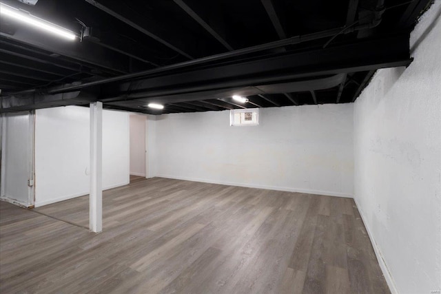 basement with baseboards and wood finished floors