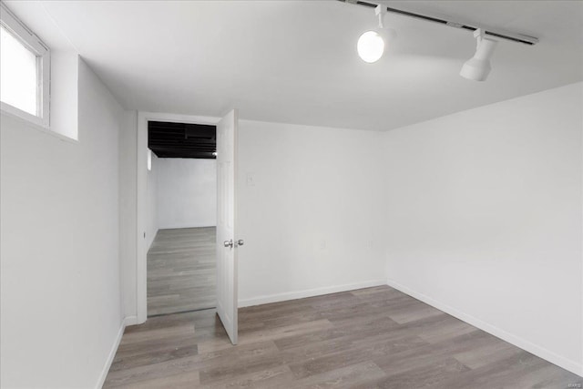 interior space featuring track lighting, wood finished floors, and baseboards