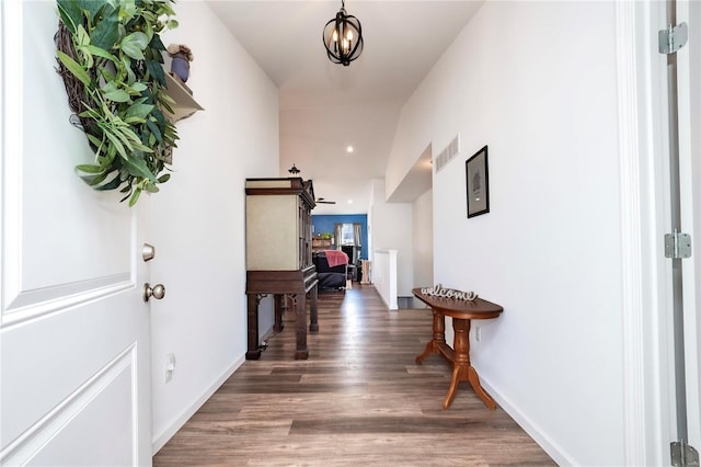 hallway featuring baseboards, a barn door, visible vents, and wood finished floors