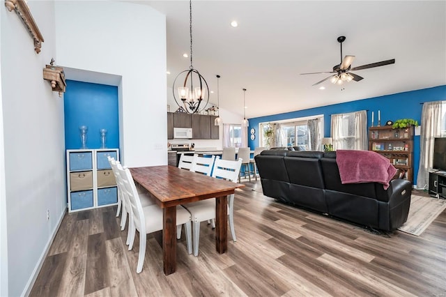 dining space with baseboards, ceiling fan with notable chandelier, wood finished floors, and recessed lighting