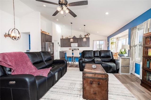 living area featuring vaulted ceiling, light wood finished floors, ceiling fan with notable chandelier, and recessed lighting