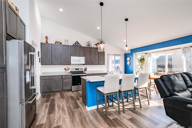 kitchen featuring open floor plan, light countertops, appliances with stainless steel finishes, and dark wood-style flooring