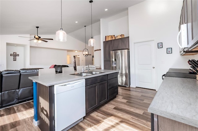 kitchen with white appliances, open floor plan, wood finished floors, light countertops, and a sink