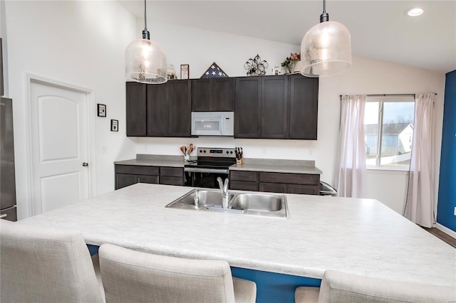 kitchen featuring white microwave, electric range, a sink, a kitchen breakfast bar, and vaulted ceiling