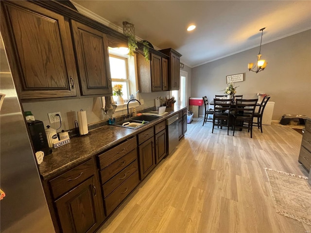 kitchen featuring light wood-type flooring, dark countertops, ornamental molding, and a sink