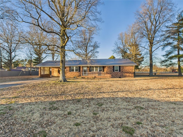 ranch-style house featuring covered porch, a carport, brick siding, and fence