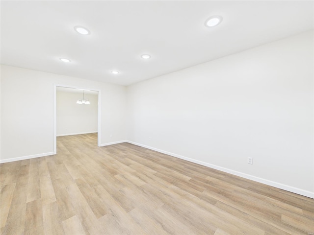 spare room featuring light wood-type flooring, baseboards, and recessed lighting