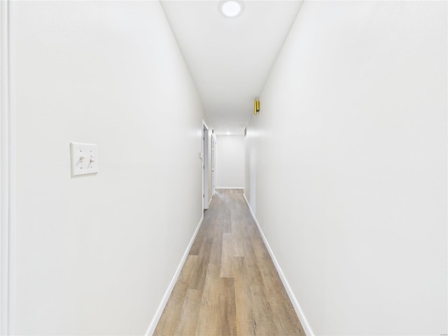 corridor featuring light wood-type flooring and baseboards