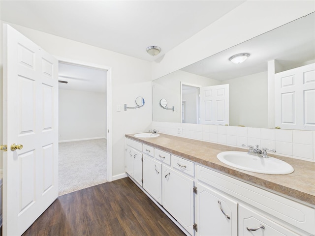 bathroom featuring tasteful backsplash, double vanity, a sink, and wood finished floors