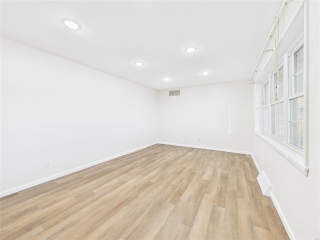 empty room featuring light wood finished floors, baseboards, visible vents, and recessed lighting