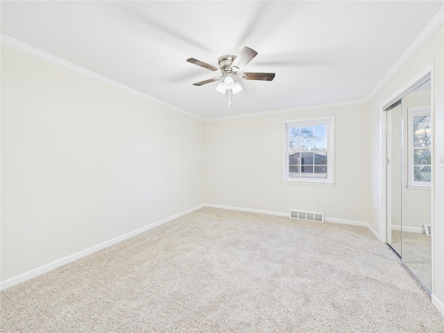 unfurnished room featuring baseboards, light colored carpet, visible vents, and crown molding