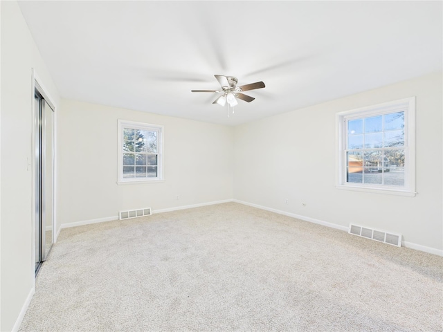 spare room with baseboards, visible vents, ceiling fan, and carpet flooring