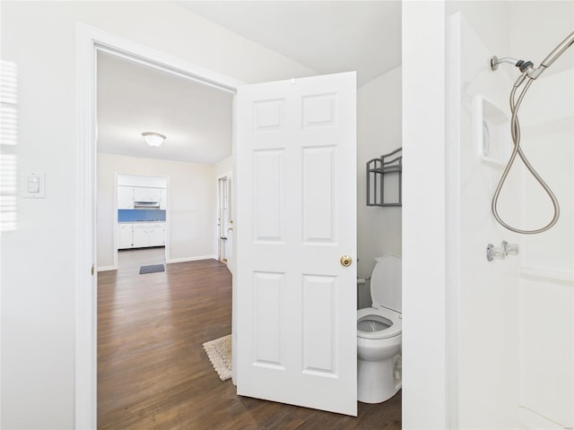 bathroom with walk in shower, wood finished floors, toilet, and baseboards