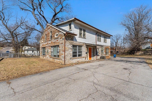 view of front of property with stone siding, fence, and a front yard