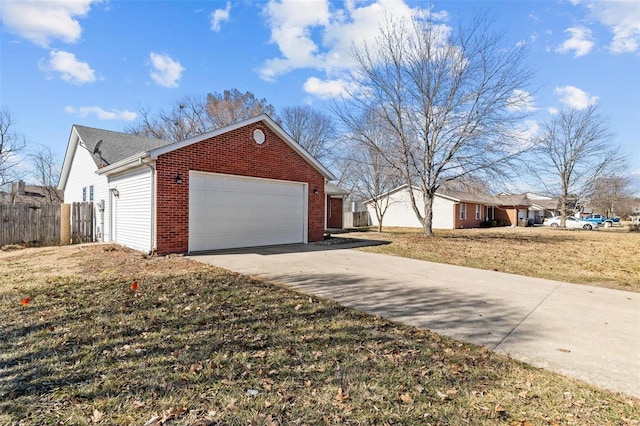 view of home's exterior with brick siding, a yard, fence, a garage, and driveway