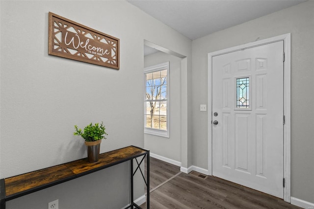 entrance foyer with dark wood-type flooring, visible vents, and baseboards