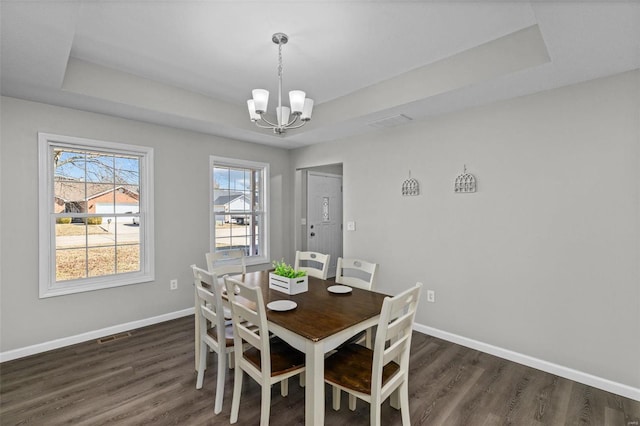 dining room with baseboards, a raised ceiling, and dark wood finished floors