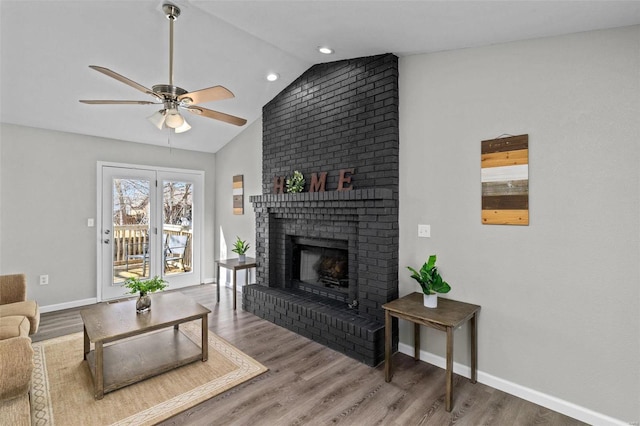 living area featuring a brick fireplace, vaulted ceiling, baseboards, and wood finished floors