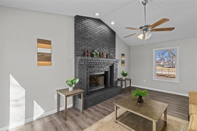 living area with a fireplace, baseboards, vaulted ceiling, and wood finished floors