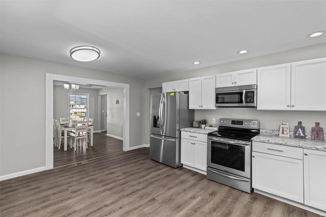 kitchen with appliances with stainless steel finishes, light wood-type flooring, and white cabinetry