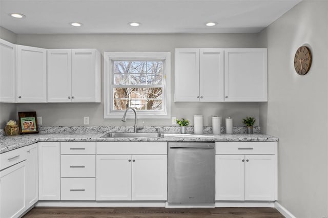 kitchen with light stone counters, stainless steel dishwasher, a sink, and white cabinetry