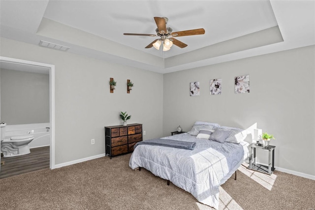 bedroom featuring a tray ceiling, carpet, visible vents, and baseboards