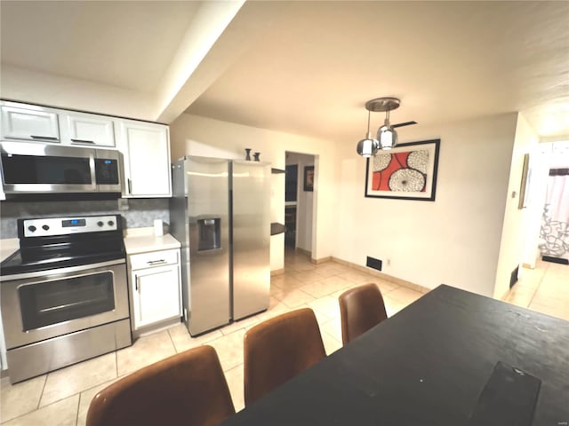 kitchen with decorative light fixtures, white cabinetry, stainless steel appliances, light tile patterned flooring, and light countertops