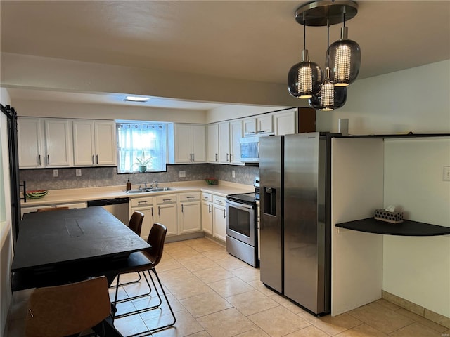 kitchen featuring light tile patterned floors, a sink, white cabinets, appliances with stainless steel finishes, and backsplash