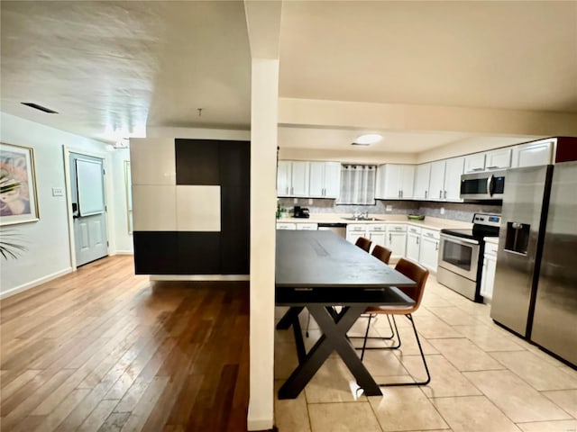 kitchen with visible vents, stainless steel appliances, white cabinets, light countertops, and baseboards